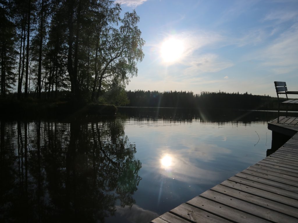 Aurinko heijastuu järven pintaan.