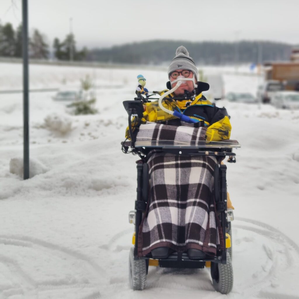 Ulkona otettu kuva minusta. Päällä on värikkäät talvivaatteet.