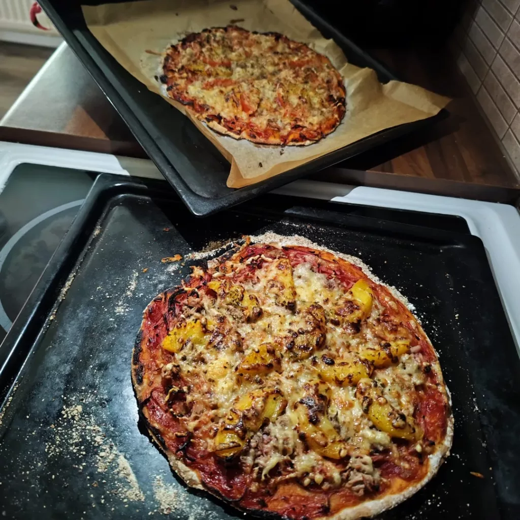 Kaksi hieman erilaista pizzaa kahdella uunipellillä.