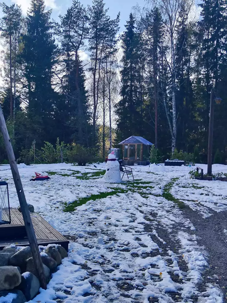 Lunta ja lumiukko talon pihalla.